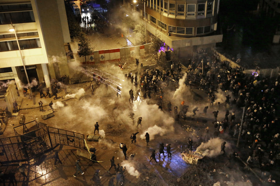 Riot police fire tear gas against anti-government protesters as they try to cross to the central government building during ongoing protests in Beirut, Lebanon, Saturday, Jan. 25, 2020. Hundreds of Lebanese gathered outside the central government building to reject the newly formed Cabinet, while some protesters breached tight security erected around it, removing a metal gate and barbed wire prompting a stream of water cannons from security forces. (AP Photo/Bilal Hussein)