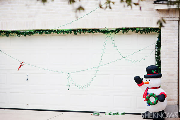 Elf on the Shelf idea 25: Elfie Rojo hanging from Christmas lights