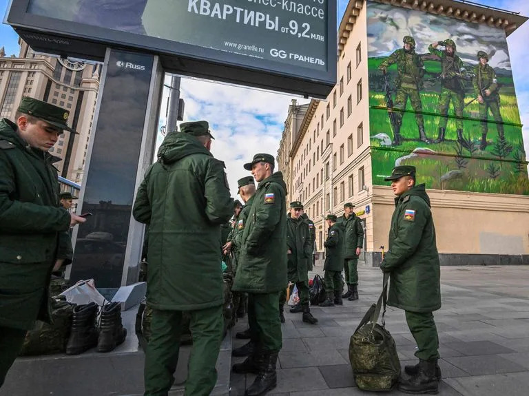 Soldados rusos esperan su salida mientras se encuentran cerca de un mural que representa a militares rusos con brazaletes con el símbolo &quot;Z&quot;, cerca de la terminal ferroviaria de Paveletsky, en el centro de Moscú el 16 de octubre de 2022.