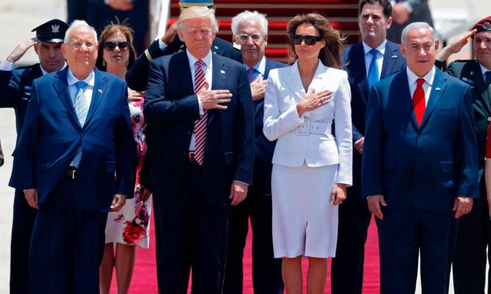 Donald and Melania Trump on a red carpet at the bottom of aircraft steps