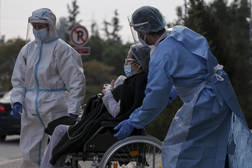 Medical personnel transfer a COVID-19 patient from a state to a private clinic which has been appropriated, in the northern city of Thessaloniki, Greece, Sunday, Nov. 29, 2020. Greece's Health ministry has forcibly appropriated two clinics and their staff in the country's second populated city, where the outbreak is the most severe. (AP Photo/Achilleas Chiras)