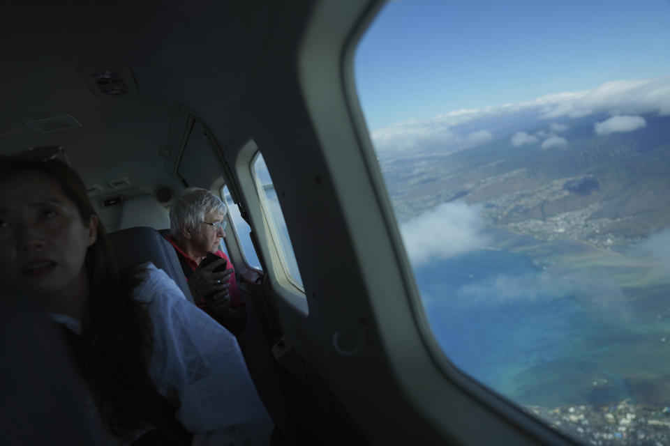 While flying to the Kalaupapa peninsula, Sister Barbara Jean Wajda of the Sisters of St. Francis of the Neumann Communities, right, looks out the window over Honolulu on Tuesday, July 18, 2023. The isolated settlement was once the government's answer to a deadly leprosy outbreak in the 1800s that persisted into the next century. (AP Photo/Jessie Wardarski)