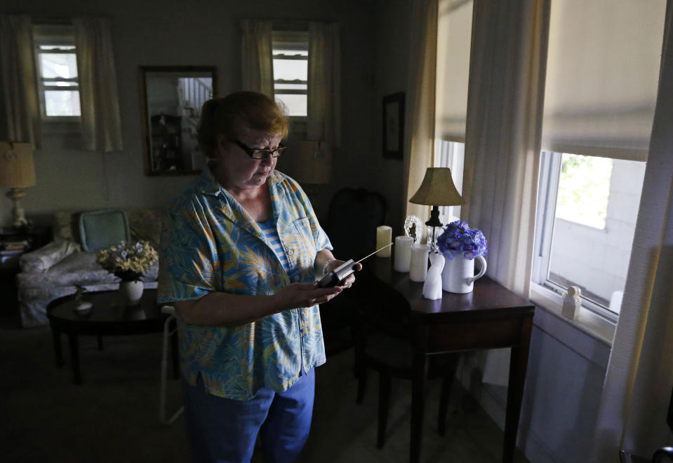 Susan Slowik tunes a battery-operated television in her living room in Baltimore, Tuesday, July 3, 2012, as she awaits the return of electricity for the first time since last weekend's severe storms. (AP Photo/Patrick Semansky)