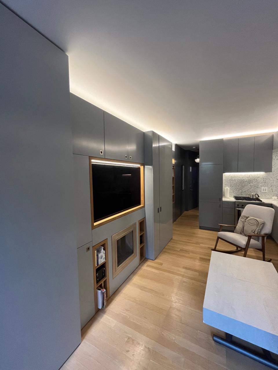 A view of the wall concealing cabinets and a bed with smooth, gray cabinetry. 