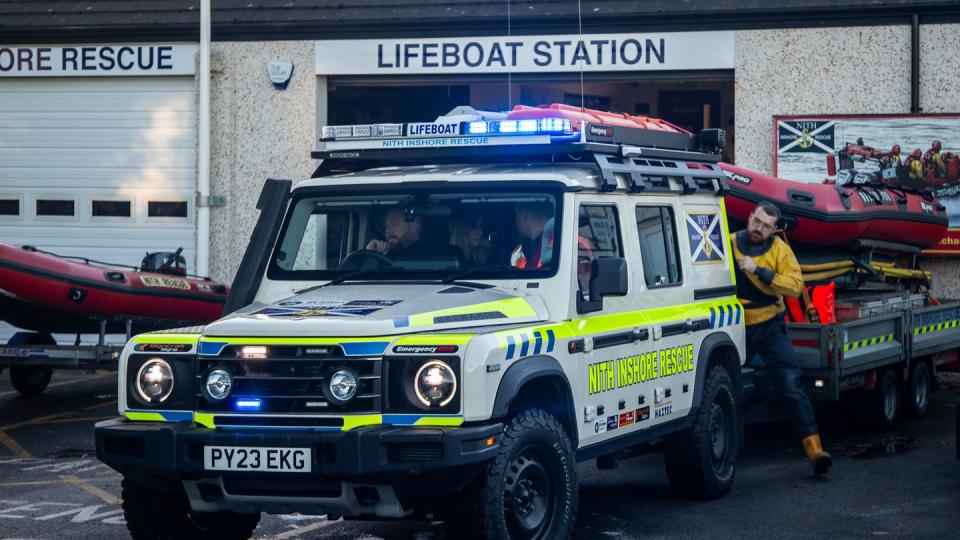 2023 ineos grenadier in uk rescue colors sits with a red inflatable boat on its trailer