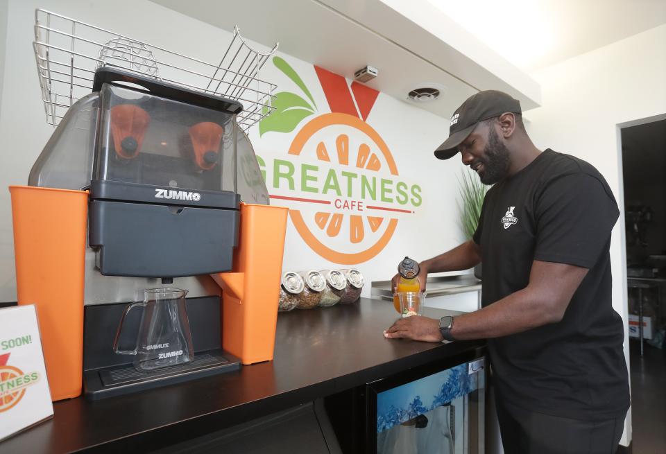 Cyrus Ausar, owner of Greatness Cafe, pours a cold pressed orange juice at the cafe in the Massillon Museum.