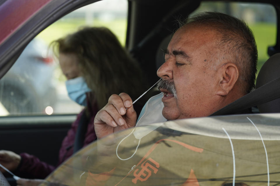 FILE - Jose Alfrtedo De la Cruz and his wife, Rogelia, self-test for COVID-19 at a No Cost COVID-19 Drive-Through event provided the GUARDaHEART Foundation for the City of Whittier community and the surrounding areas at the Guirado Park in Whittier, Calif., on Tuesday, Jan. 25, 2022. Omicron, the highly contagious coronavirus variant sweeping across the country, is driving the daily American death toll higher than during last fall's delta wave, with deaths likely to keep rising for days or even weeks. (AP Photo/Damian Dovarganes)