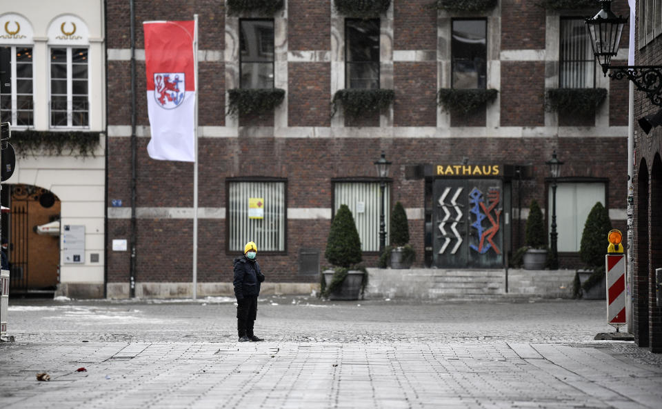 A lonely man looks in front of the town hall at the empty old town of Duesseldorf Duesseldorf, Germany, Monday, Feb. 15, 2021. Because of the coronavirus pandemic the traditional; carnival parades are canceled but eight floats are pulled through the empty streets in Duesseldorf, where normally hundreds of thousands of people would celebrate the street carnival. (AP Photo/Martin Meissner)