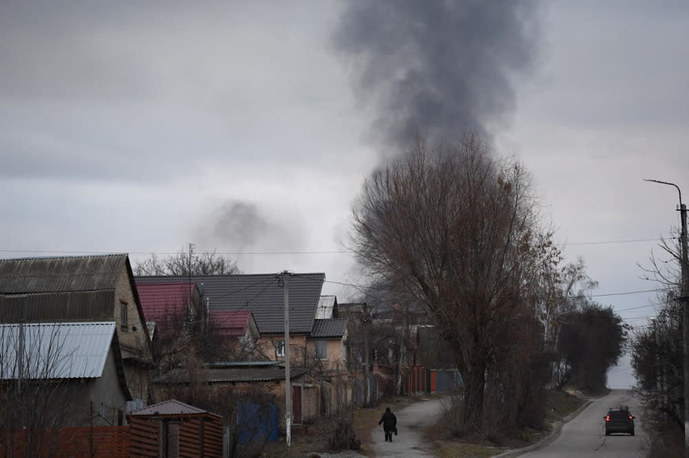 A local resident walks in a street as smoke rises near the town of Hostomel and the Antonov Airport, in northwest Kyiv on February 24, 2022. — AFP pic