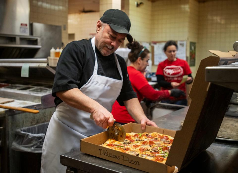 Woosta Pizza owner Andrea Gramo cuts a pizza in the kitchen Wednesday.