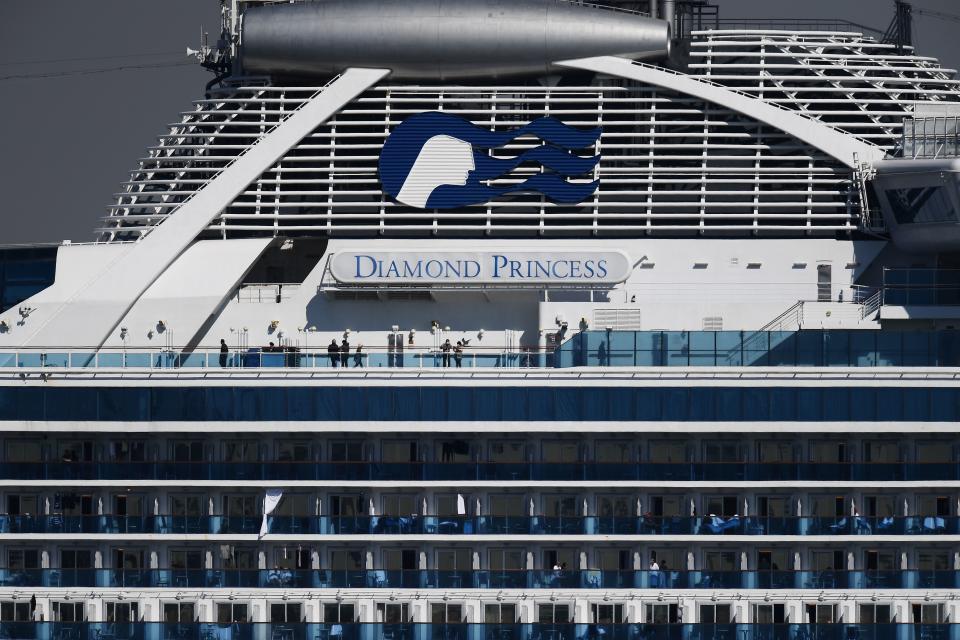 Passengers stand on balconies on the Diamond Princess cruise ship, with around 3,600 people quarantined onboard due to fears of the new coronavirus, at the Daikoku Pier Cruise Terminal in Yokohama port on February 10, 2020. - Around 60 more people on board the quarantined Diamond Princess cruise ship moored off Japan have been diagnosed with novel coronavirus, the country's national broadcaster said on February 10, raising the number of infected passengers and crew to around 130. (Photo by CHARLY TRIBALLEAU / AFP) (Photo by CHARLY TRIBALLEAU/AFP via Getty Images)