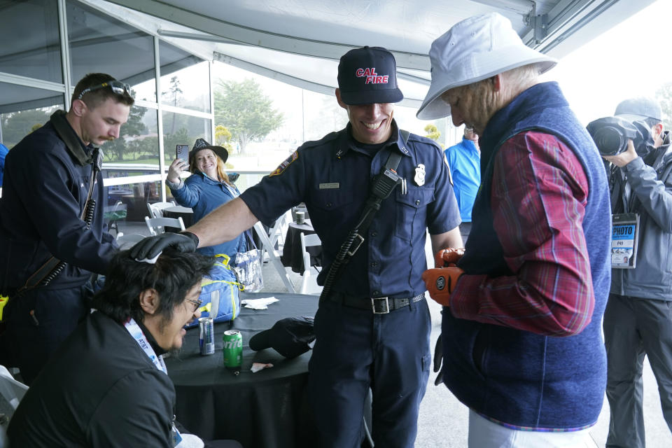 Bill Murray, right, stops to sign a ball for Umberto Garcia, of Newark, Calif., seated, after Garcia was hit in the head by Murray's drive from the third tee of the Pebble Beach Golf Links during the third round of the AT&T Pebble Beach Pro-Am golf tournament in Pebble Beach, Calif., Saturday, Feb. 4, 2023. Garcia, whose bleeding head was treated by paramedics, was on the deck of the Patriot's Outpost that looks out over the third hole. (AP Photo/Eric Risberg)