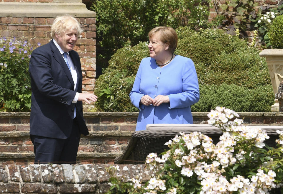 Britain's Prime Minister Boris Johnson, left, and German Chancellor Angela Merkel, walk through the garden at Chequers, the country house of the Prime Minister, in Buckinghamshire, England, Friday July 2, 2021. Johnson is likely to push Angela Merkel to drop her efforts to impose COVID-19 restrictions on British travelers as the German chancellor makes her final visit to Britain before stepping down in the coming months. Johnson will hold talks with Merkel at his country residence on Friday. (Stefan Rousseau/Pool Photo via AP)