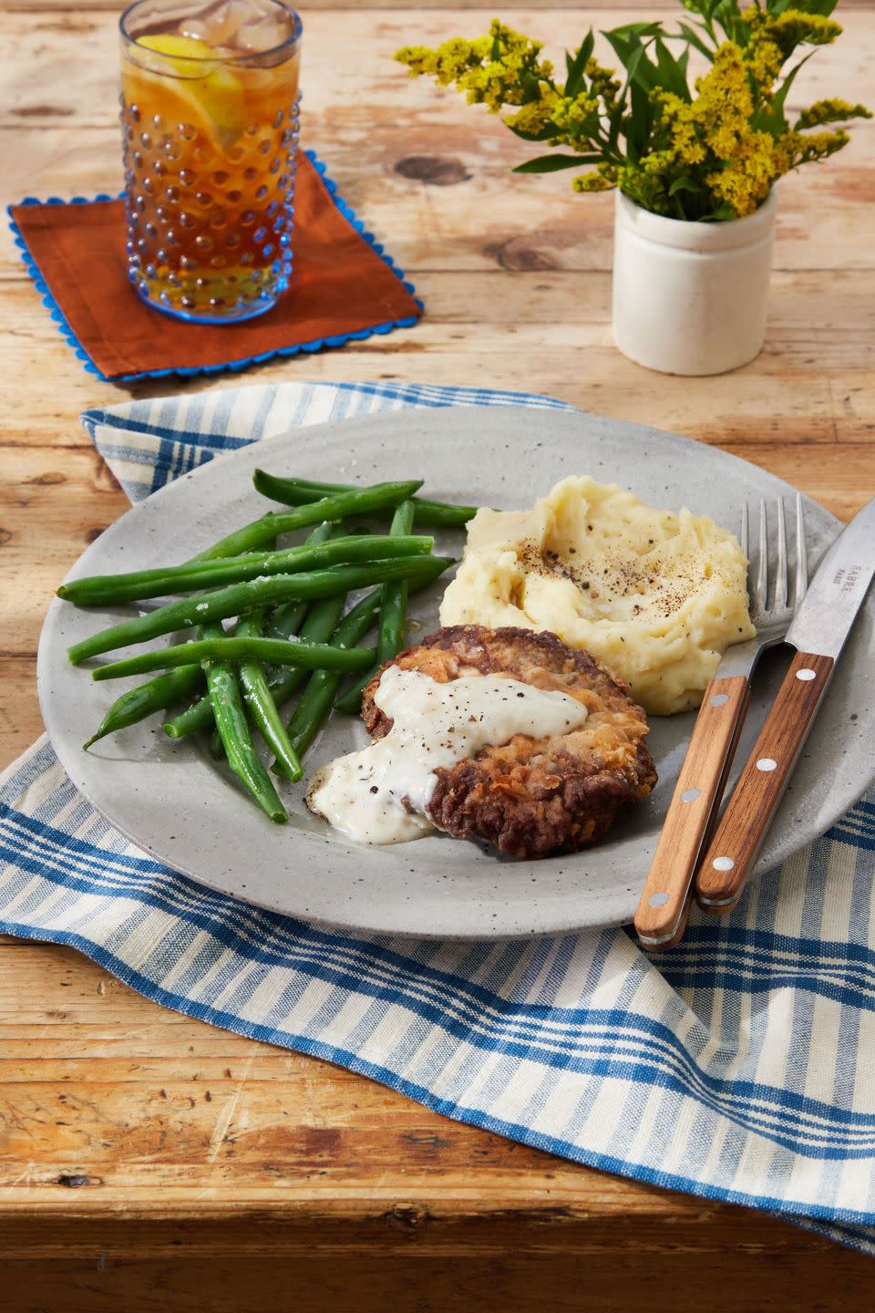 chicken fried steak on a plate with green beans and mashed potatoes