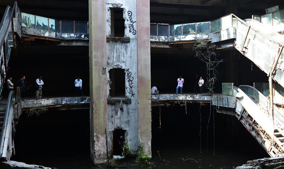 water covers the floor of a shopping mall in ruins