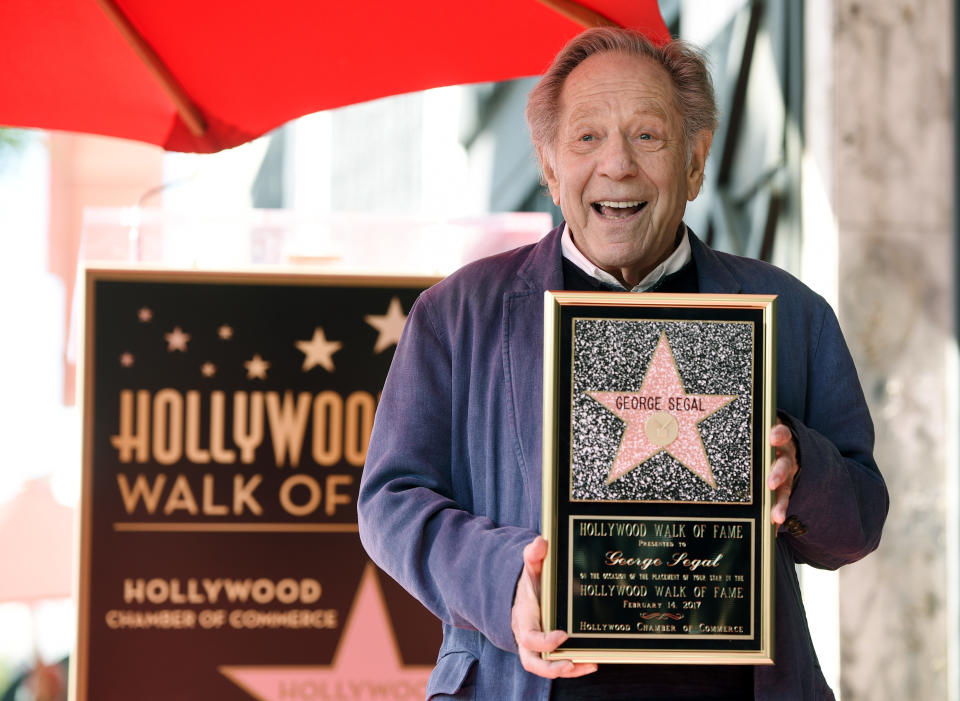 FILE - Actor George Segal poses with a replica of his star at a ceremony honoring him on the Hollywood Walk of Fame in Los Angeles on Feb. 14, 2017. Segal, the banjo player turned actor who was nominated for an Oscar for 1966's “Who’s Afraid of Virginia Woolf?,” and starred in the ABC sitcom “The Goldbergs,” died Tuesday, his wife said. He was 87. (Photo by Chris Pizzello/Invision/AP, File)