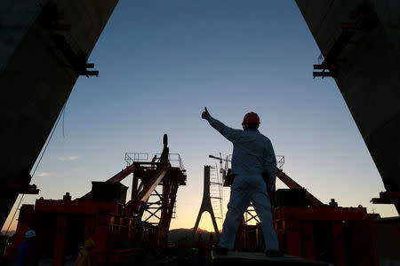 Workers are seen silhouetted at a construction site of Fuchimen Bridge in Zhoushan, Zhejiang province, China July 14, 2018. Picture taken July 14, 2018. REUTERS/Stringer