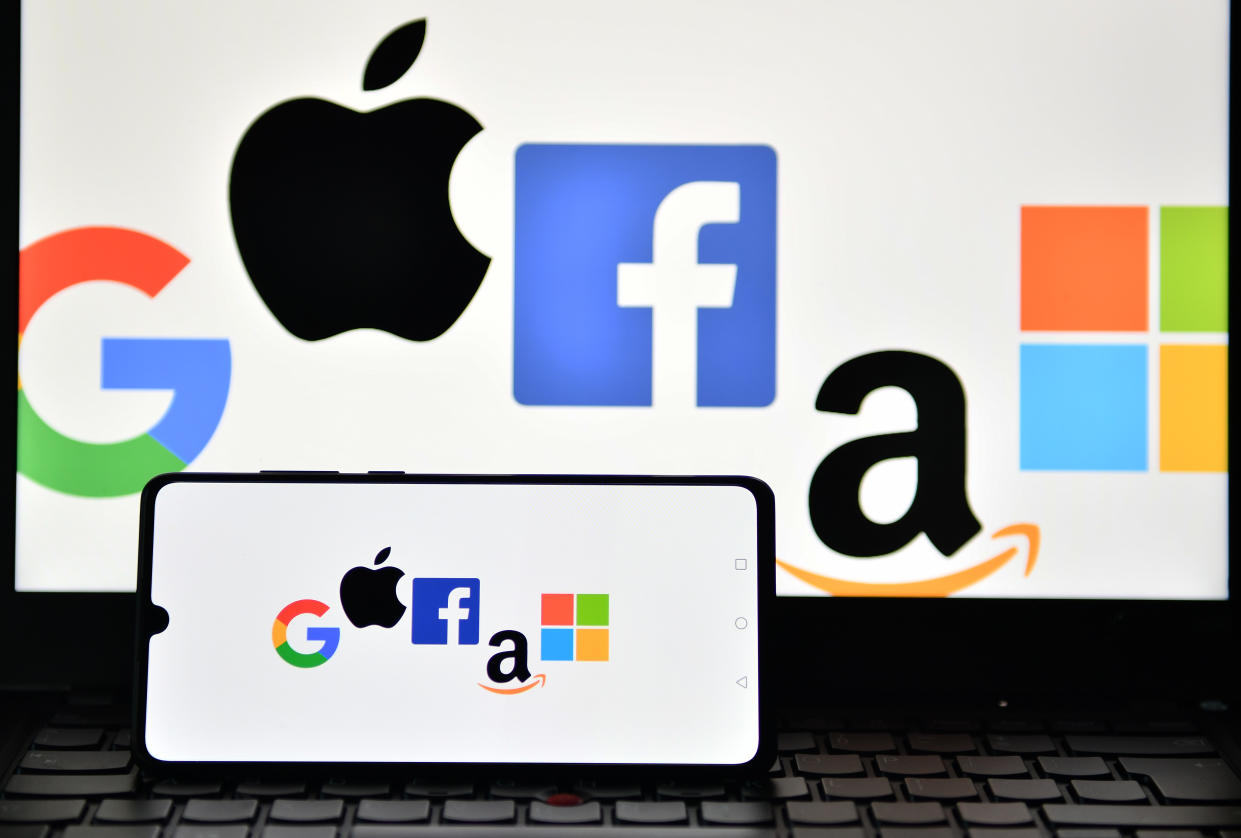 An illustration picture taken in London on December 18, 2020 shows the logos of Google, Apple, Facebook, Amazon and Microsoft displayed on a mobile phone and a laptop screen. - The European Union on December 15 unveiled tough draft rules targeting tech giants like Google, Amazon and Facebook, whose power Brussels sees as a threat to competition and even democracy. (Photo by JUSTIN TALLIS / AFP) (Photo by JUSTIN TALLIS/AFP via Getty Images)