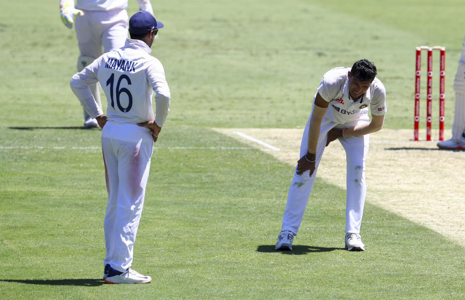 India's Navdeep Saini, right, reacts after injuring his leg while bowling during play on the first day of the fourth cricket test between India and Australia at the Gabba, Brisbane, Australia, Friday, Jan. 15, 2021. (AP Photo/Tertius Pickard)