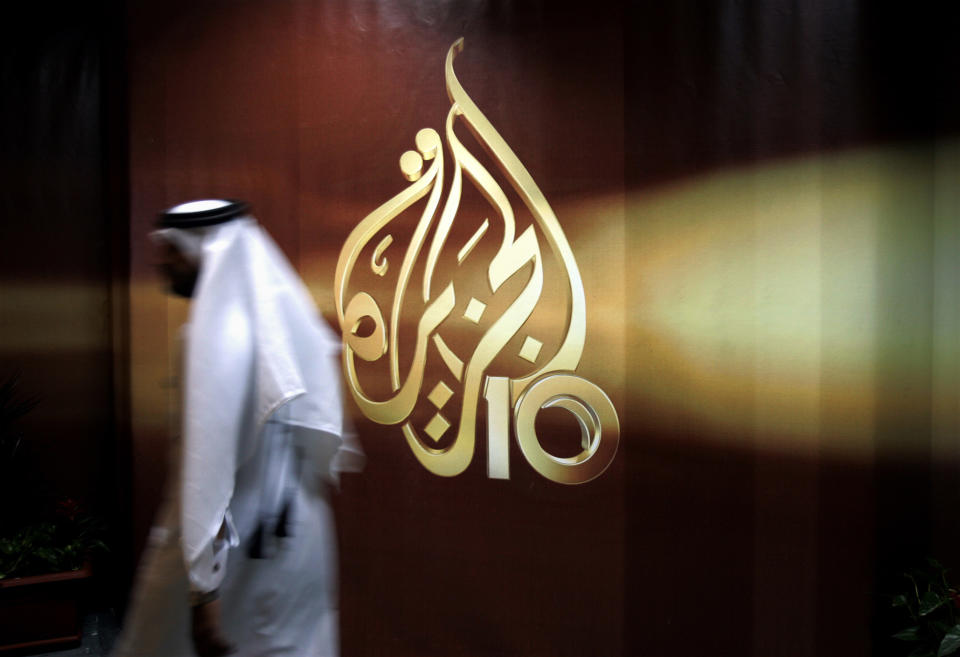 FILE - In this Nov. 1, 2006 file photo, a Qatari employee of Al-Jazeera Arabic language TV news channel walks past the logo of Al-Jazeera in Doha, Qatar. An Egyptian court on Thursday, May 23, 2019, ordered the release of an Al-Jazeera journalist who had been detained since 2016 on allegations of spreading false news and defaming Egypt’s reputation. Mahmoud Hussein, an Egyptian journalist working for the Qatar-based satellite network, was detained at the Cairo airport in December 2016 when he arrived on a family vacation from Doha. No official charges were ever raised against him and Hussein didn’t stand trial. (AP Photo/Kamran Jebreili, File)