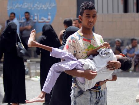 A displaced boy from Hodeidah city carries his brother who is affected by monoplegia, at a school where displaced people live, in Sanaa, Yemen June 22, 2018. REUTERS/Mohamed al-Sayaghi