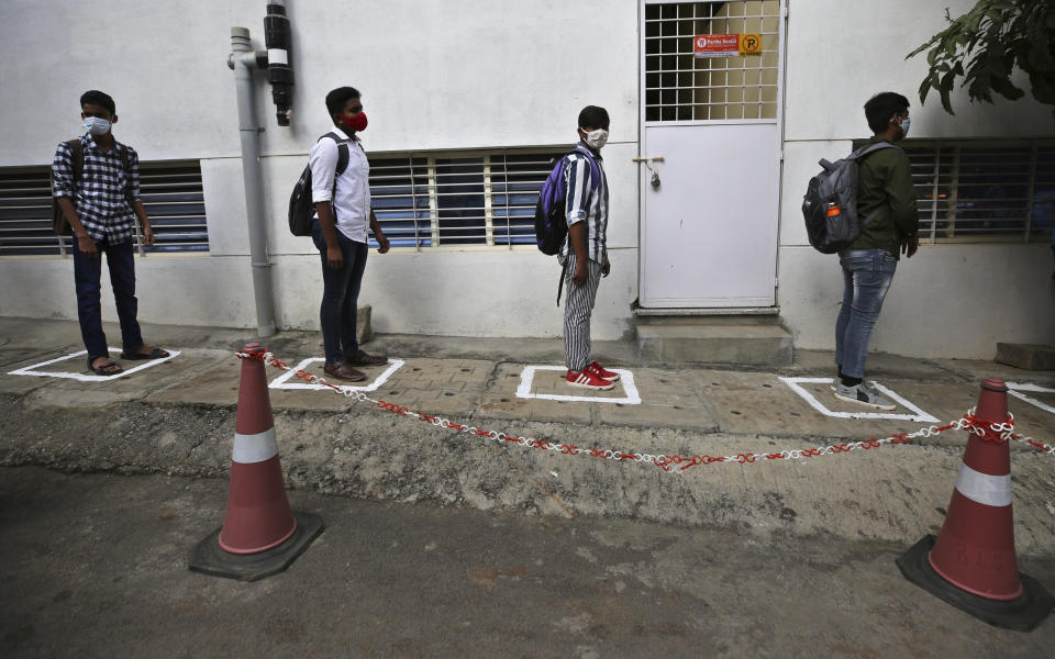 Students wearing face masks and maintain social distancing as a precaution against the coronavirus wait to enter the school in Bengaluru, India, Friday, Jan. 1, 2021. The southern state of Karnataka on Friday opened schools for students of grade 10 and 12 after a gap of more than nine months. India has more than 10 million cases of coronavirus, second behind the United States. (AP Photo/Aijaz Rahi)