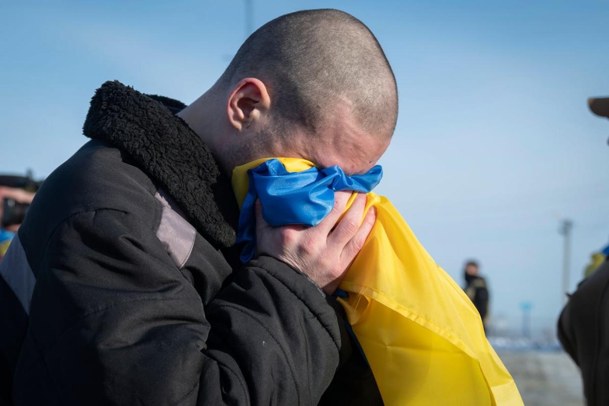 This photograph, shared by Ukrainian President Volodymyr Zelenskyy on the social media platform X on Wednesday, Jan. 31, 2024, shows Ukrainian prisoners of war reacting after a prisoner exchange at an undisclosed location in Ukraine.  (Ukrainian President Volodymyr Zelenskyy on the social media platform X via AP - image credit)