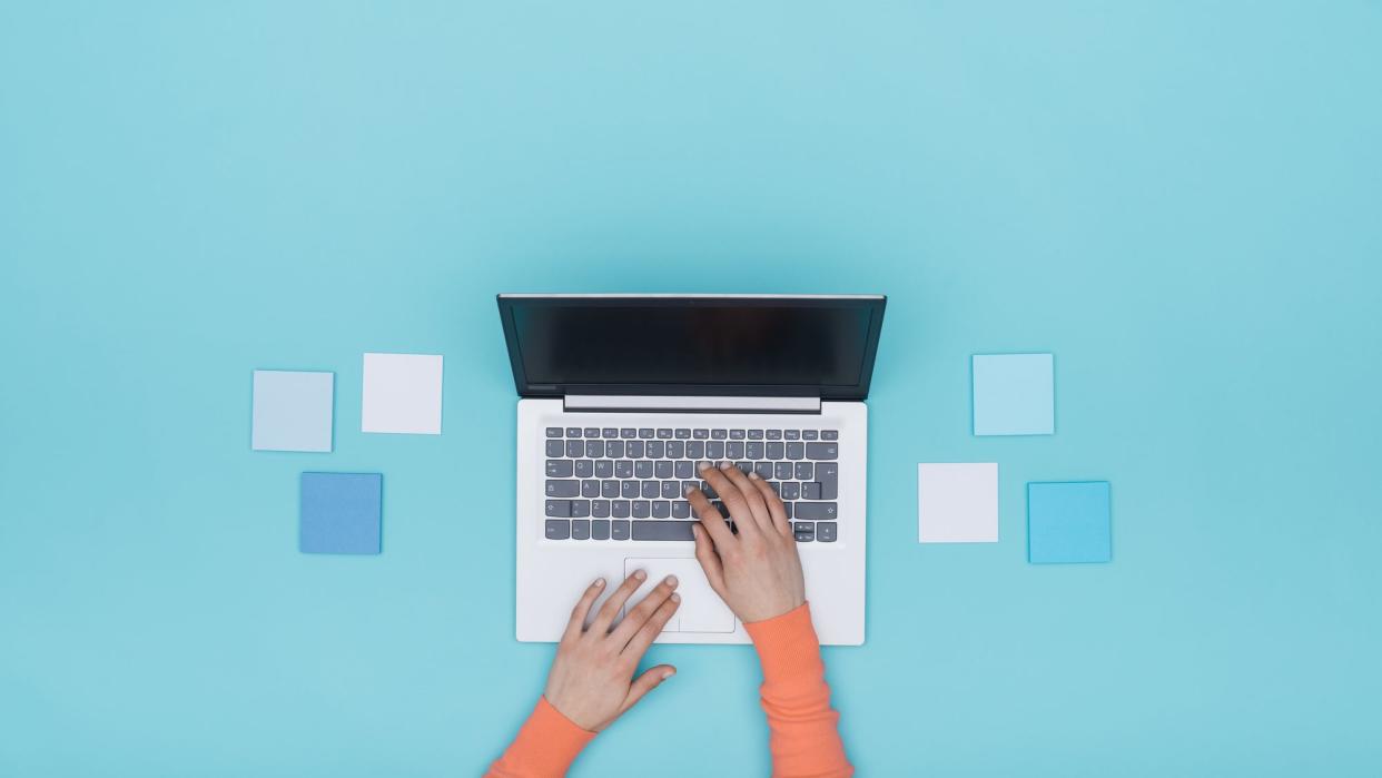 Woman working with a laptop and sticky notes