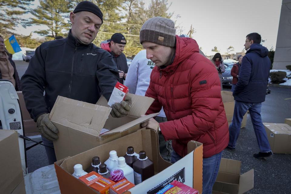 FILE - Volunteers Slavko Oleinik, of Framingham, Mass., left, and Victor Pishuk, of Newton, Mass., right, place medical supplies in boxes for shipment to Ukraine, on March 2, 2022, in Woburn, Mass. When Russian forces two months ago launched a military campaign against infrastructure in Ukraine, it opened an urgent second front far from the contact line: along power lines, water mains, and heating systems, and in places like homes, schools, offices and churches. (AP Photo/Steven Senne, File)