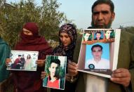 Pakistani parents display photographs of their children who were killed in 2014 when Taliban gunmen attacked an army-run school in Peshawar