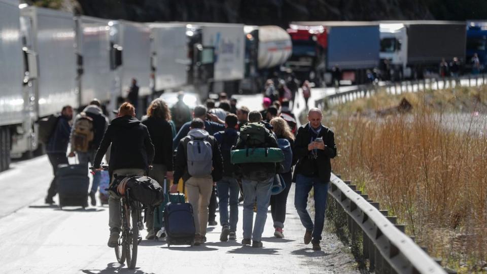 Hombres con maletas cruzan la frontera entre Rusia y Georgia.