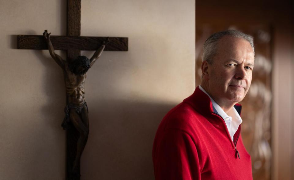 Tim Busch stands in front of a crucifix.