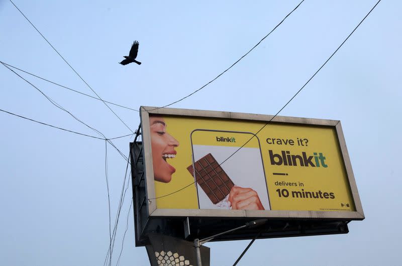 A bird flies over a hoarding featuring an advertisement of the SoftBank-funded Blinkit in New Delhi