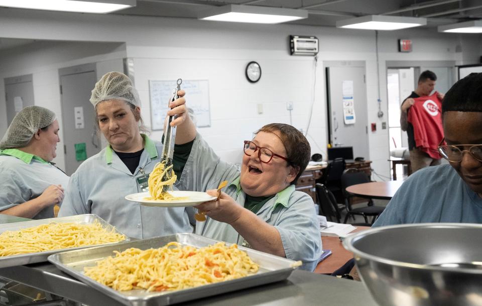 Jennifer Bainbridge smiles and laughs as she tries to plate pasta in a pile as her instructor showed during a cooking class through Sinclair Community College at the Ohio Reformatory for Wome