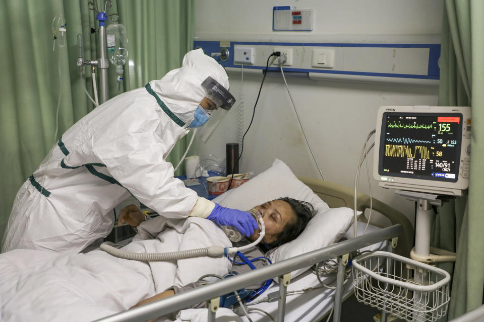 In this Thursday, Feb. 6, 2020, photo, a nurse feeds water to a patient in the isolation ward for 2019-nCoV patients at a hospital in Wuhan in central China's Hubei province. The number of confirmed cases of the new virus has risen again in China Saturday, Feb. 8, 2020, as the ruling Communist Party faced anger and recriminations from the public over the death of a doctor who was threatened by police after trying to sound the alarm about the disease over a month ago. (Chinatopix via AP)
