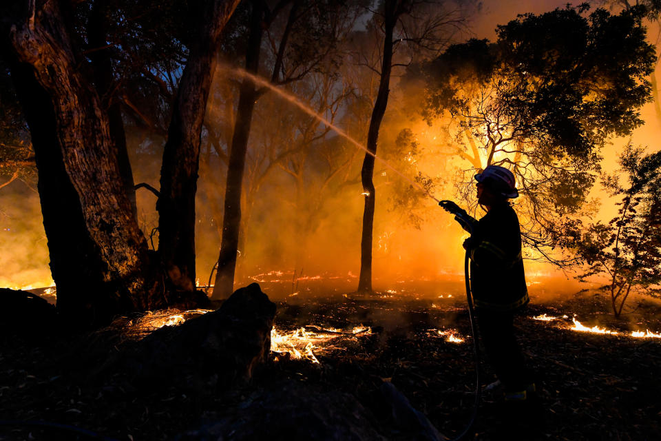 Firefighters spray a blaze in Yanchep, Western Australia, with water. Source: AAP