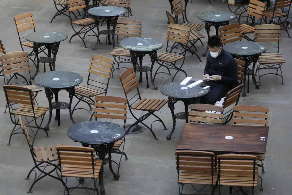 A man sits in an empty cafe in London, Thursday, Sept. 24, 2020, after Britain's Prime Minister Boris Johnson announced a range of new restrictions to combat the rise in coronavirus cases in England. (AP Photo/Kirsty Wigglesworth)