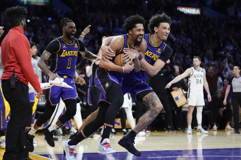 Los compañeros de equipo de los Lakers, Jaxson Hayes, derecha, Spencer Dinwiddie, centro, y D'Angelo Russell celebran su victoria sobre los Bucks.