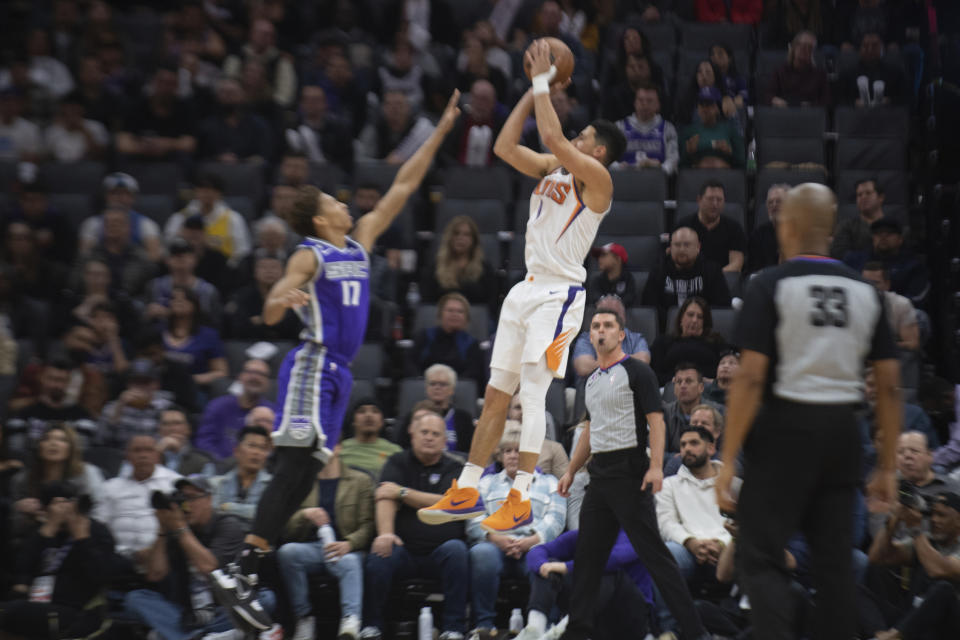 Phoenix Suns guard Devin Booker (1) shoots over Sacramento Kings guard Kessler Edwards (17) in the first quarter in an NBA basketball game in Sacramento, Calif., Friday, March 24, 2023. (AP Photo/José Luis Villegas)