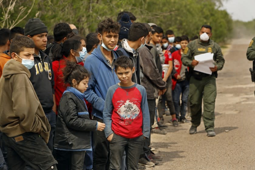 LA JOYA, TEXAS—March 25, 2021—Ten-year-old Christopher Garcia, center, sits with fellow Central American migrants in Texas's Rio Grande Valley waiting transport to a Border Patrol holding area on March 25, 2021.(PLEASE REFER TO STORY ON ID) Christopher traveled alone from San Pedro Sula, Honduras to reach the United States. The journey took about a month before he crossed the Rio Grande River last week and was detained by Border Patrol in La Joya, Texas on March 25, 2021. He was carrying only his birth certificate from Honduras. He hopes to reach his aunt in North Carolina, but is currently detained at the Donna facility in Donna, Texas. Christopher, a skinny boy with curly brown hair and an impish smile, was at an age when the street gangs that dominated his neighborhood had started to recruit him. His father, who worked at a clothes factory, had already tried to migrate to the U.S. but was deported the day he crossed the border two years ago. The number of unaccompanied minors crossing illegally from Mexico into the United States is unprecedented, overwhelming Border Patrol. (Carolyn Cole / Los Angeles Times)