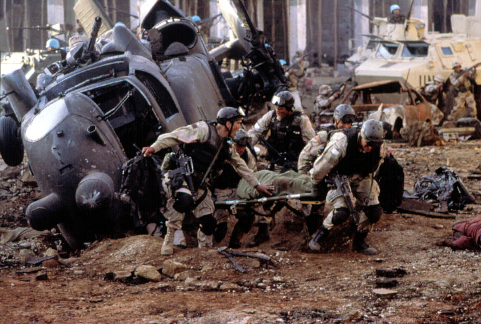 The cast including Ty Burrell and Jeremy Piven as soldiers carrying a wounded comrade on a stretch next to a downed helicopter in a scene from the movie