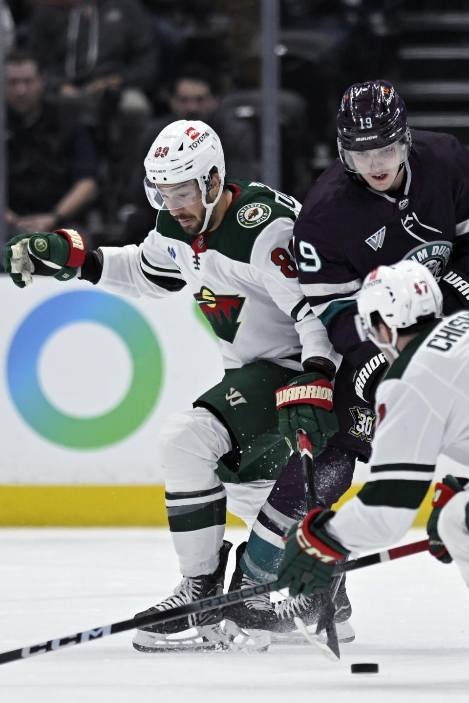 Minnesota Wild center Frederick Gaudreau (89) and Anaheim Ducks right wing Troy Terry (19) vie for the puck next to Ducks defenseman Declan Chisholm (47) during the first period of an NHL hockey game in Anaheim, Calif., Tuesday, March 19, 2024. (AP Photo/Alex Gallardo)