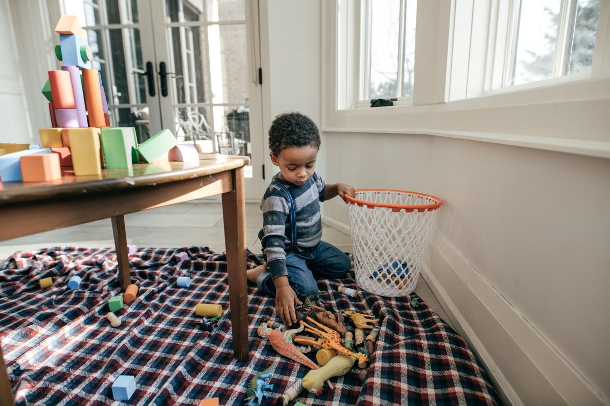 little boy putting toys in basket