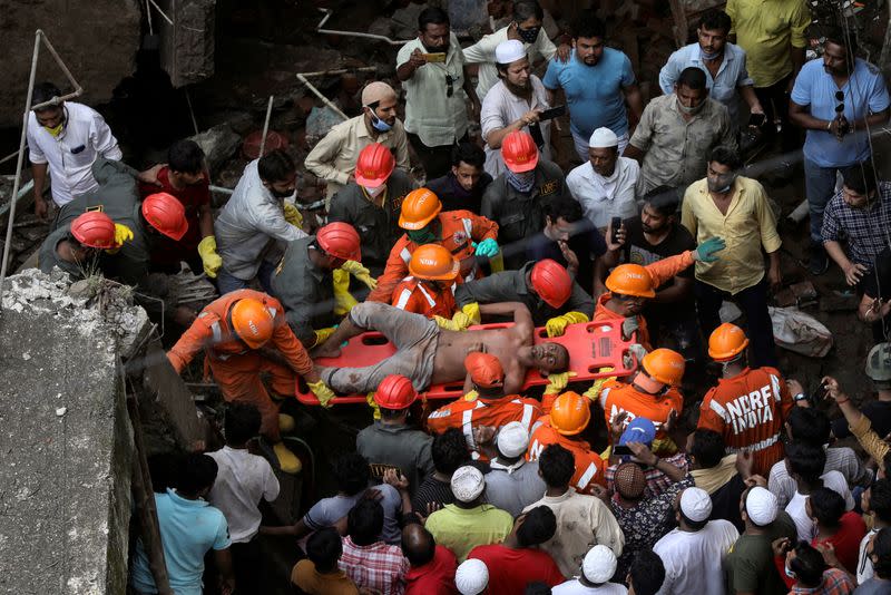National Disaster Response Force (NDRF) officials rescue a man from the debris after a three-storey residential building collapsed in Bhiwandi on the outskirts of Mumbai, India