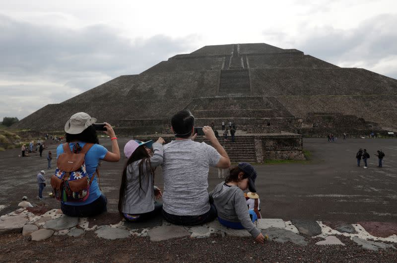 Members of a family take pictures with their cell phones as they wear protective masks during the start of the gradual reopening of the ancient ruins of Teotihuacan