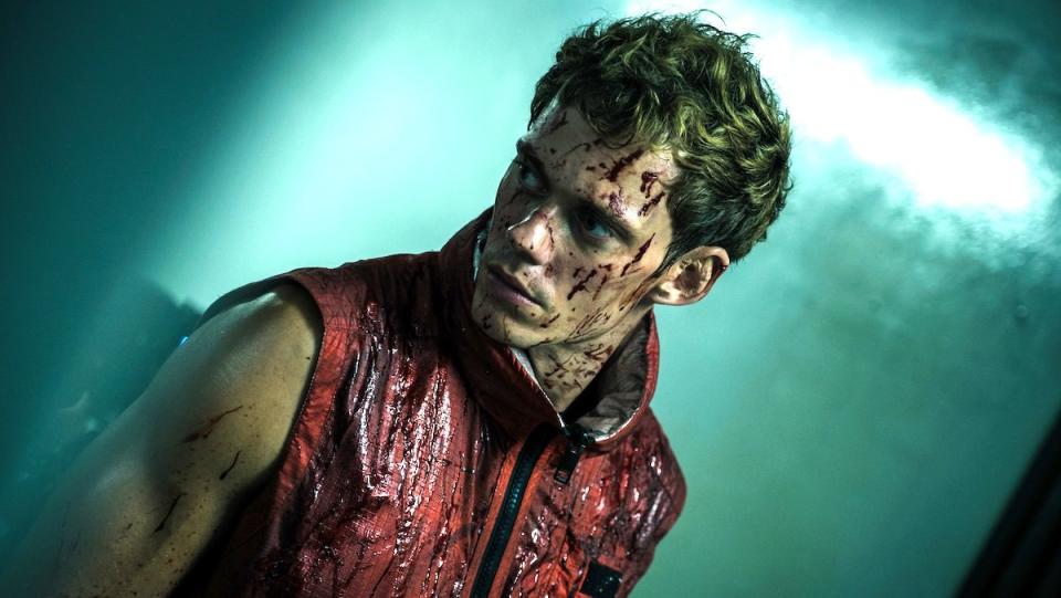 A bloodied Bill Skarsgård in a red vest in Boy Kills World