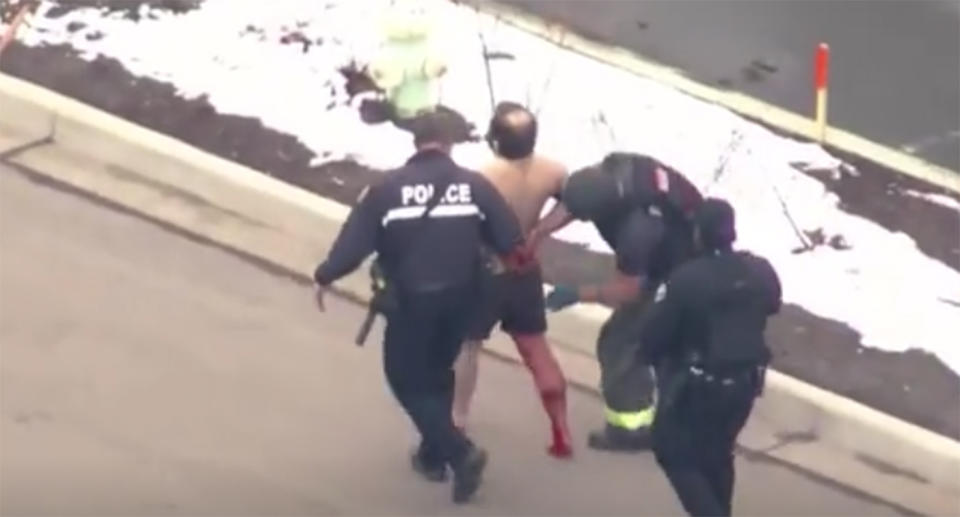 Police officers surround a man with what appears to blood running down his leg in the wake of a shooting in Boulder, Colorado.