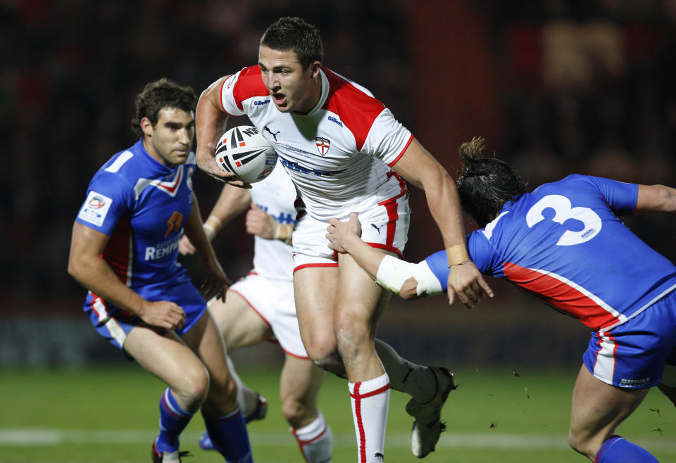 FILE - In this Friday, Oct. 23, 2009 file photo, England's Sam Burgess, centre, is tackled by France's Sebastien Raguin, right, during their Four Nations rugby league match at the Keepmoat Stadium, Doncaster, England. Sam Burgess is switching rugby codes, from league to union, in a bid to become a World Cup winner with England in 2015. The English rugby league forward, who has scored seven tries in 13 international appearances, has signed a three-year deal to join English rugby side Bath and leave the South Sydney Rabbitohs of Australia's National Rugby League after four years. "An opportunity presented itself to head back home to England and to pursue a chance to represent my country in two different sports," Burgess said Monday. Feb. 17, 2014 on the Rabbitohs website. (AP Photo/Jon Super, File)