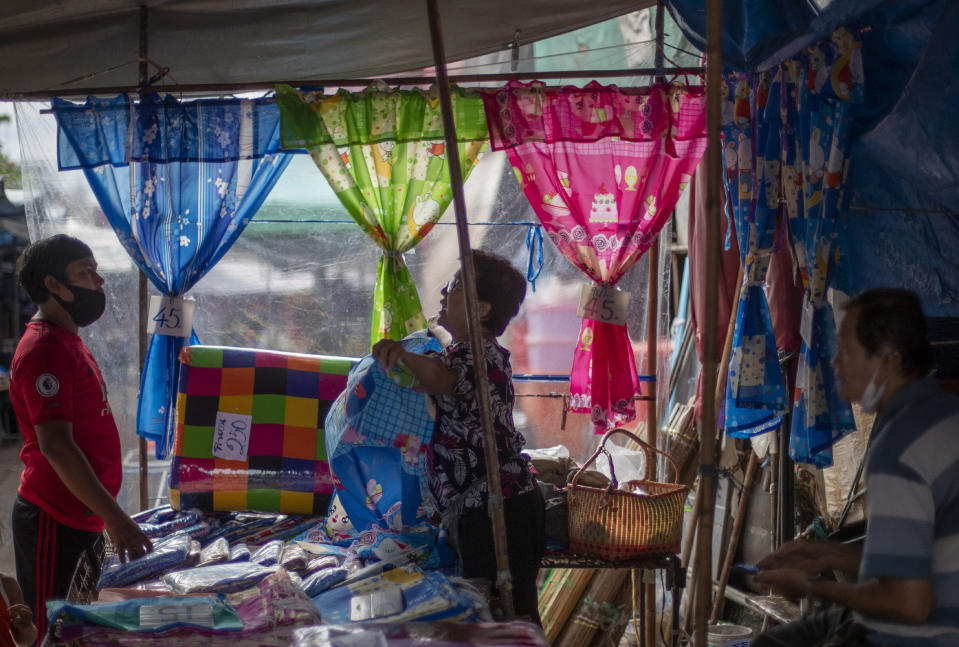 A fabric vender negotiates with a buyer at a roadside shop in Bangkok, Thailand, Wednesday, Aug. 5, 2020. Thailand has managed to curb COVID-19 infections over the last three months with strict controls on entry into the country and aggressive testing and quarantine requirements. But its economy is expected to contract by at least 5% in 2020, according to the World Bank. (AP Photo/ Gemunu Amarasinghe)