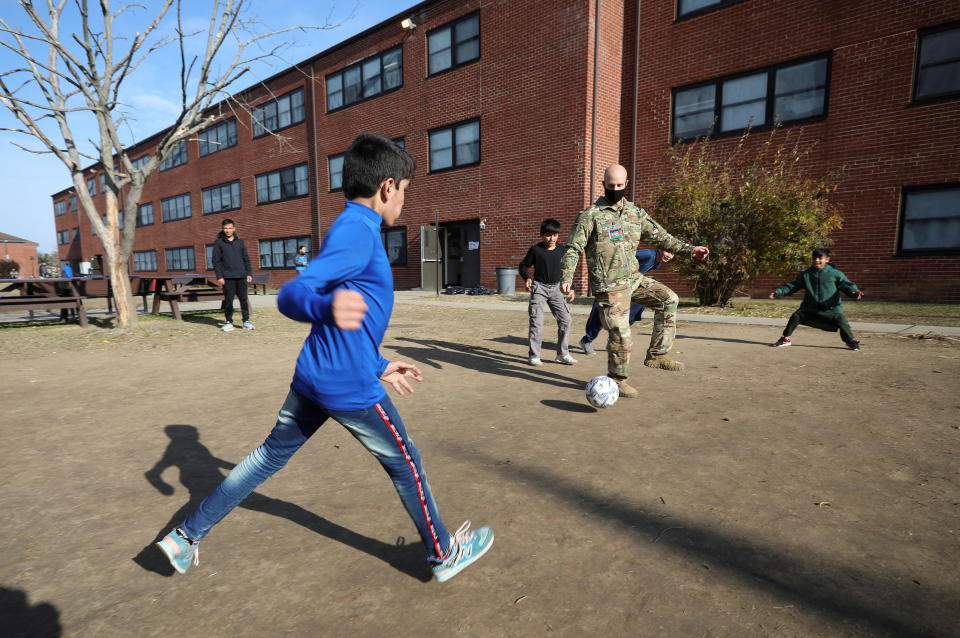 Afghan children play soccer with U.S. Air Force Tech. Sgt. Scott Nussel, a cultural awareness specialist, outside a temporary housing in Liberty Village on Joint Base McGuire-Dix-Lakehurst in New Jersey, on December 2, 2021. / Credit: BARBARA DAVIDSON / REUTERS